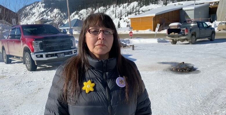 Woman wearing a yellow flower pin standing outside.