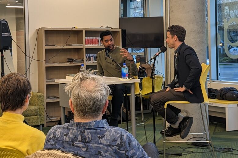 A host and an author engage in conversation in a library