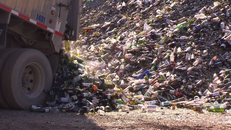 a dump truck in a landfill full of glass bottles