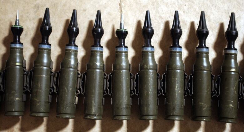 A row of dark, military green bullets with pointed ends. 