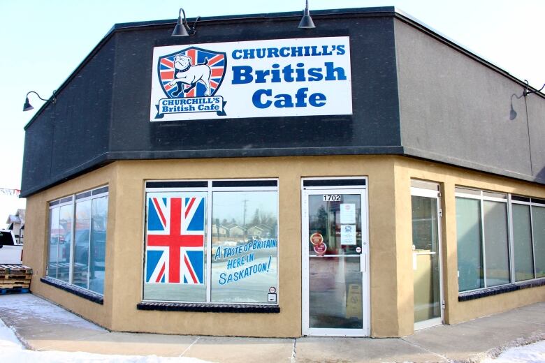 The front windows of a one-storey building are decorated with a British flag and a decal that reads 