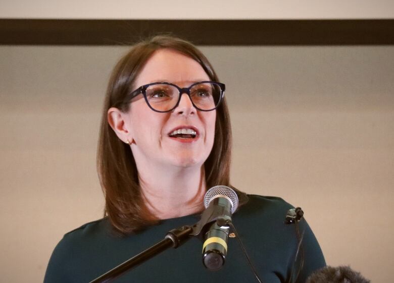 A woman in glasses looks up and smiles.