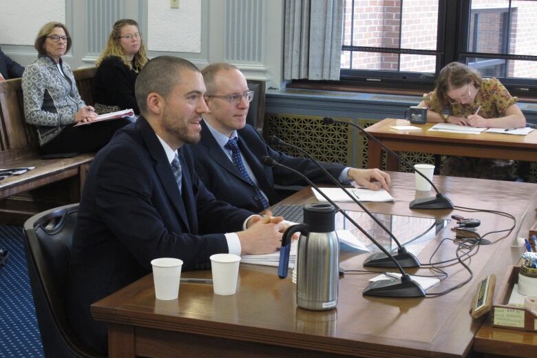 Two men sit at a table together.