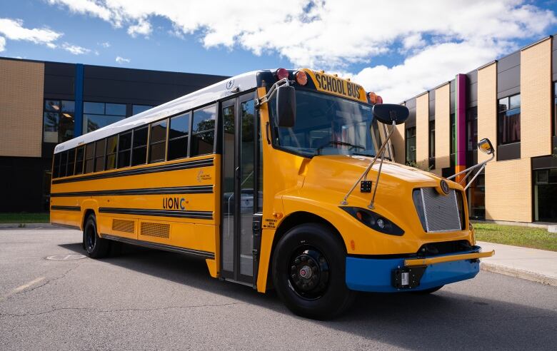 An electric school bus is parked outside a building.