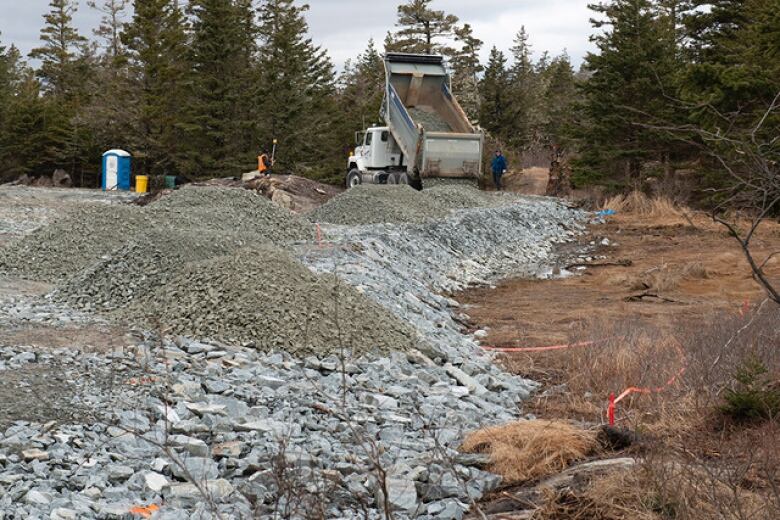 Truck dumps gravel out into a pile.