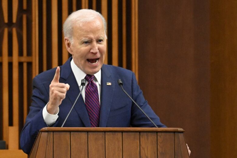 A person gestures while speaking at a lectern.