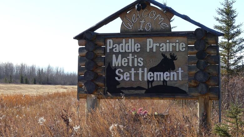 A large wooden sign beside a highway, with the words Welcome to Paddle Prairie  Mtis Settlement.