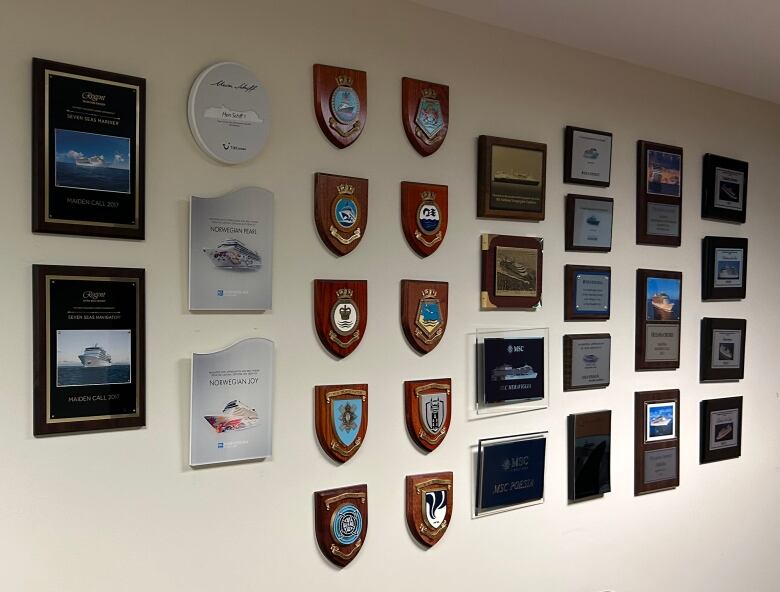 A number of plaques hang on a grey wall.