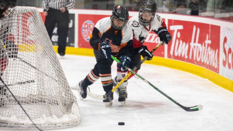 Two under 13 hockey players battle for the puck.