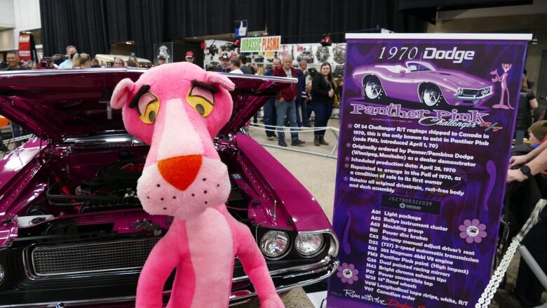 A stuffed panther in front of a car.