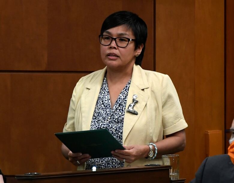 Woman in glasses standing to speak. 