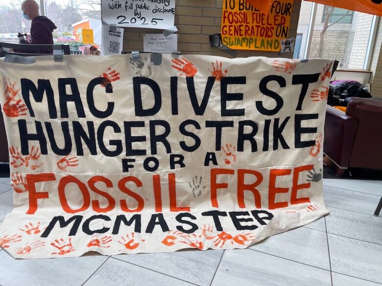 A banner on display at a Mc Divest rally on Friday, March 24, 2023.