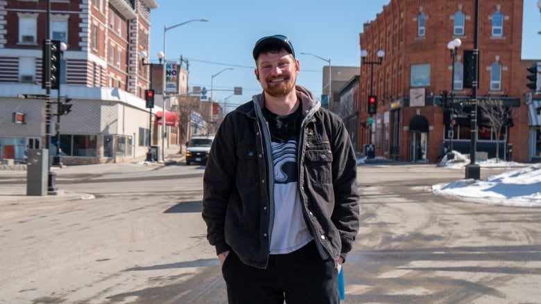 A man stands on a road, smiling.