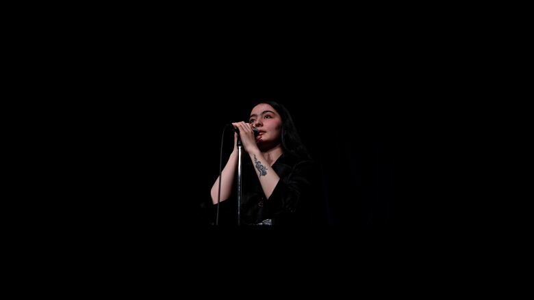 Farhang Nesar stands at a microphone on stage at her school, Nutana Collegiate in Saskatoon.