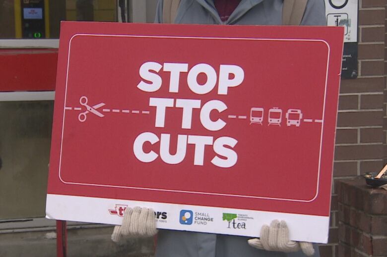 A member of TTCriders holds up a sign outside Spadina subway station on Monday morning.