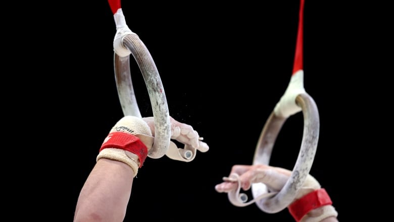 A close-up view of hands on rings during a gymnastics competition.