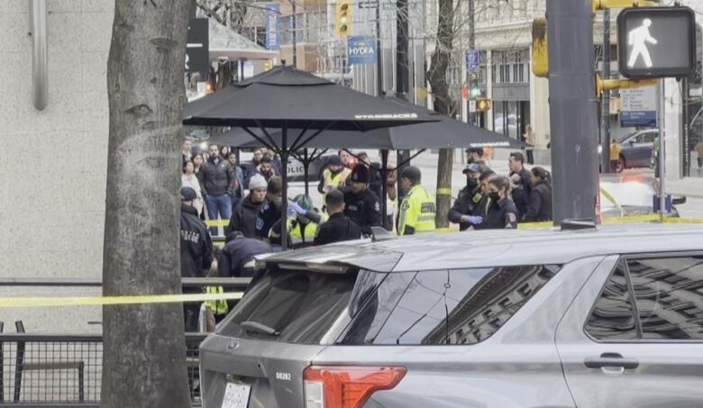 From a distance away, a half dozen or so paramedics and other first responders provide medical care to a man on the ground who cannot be seen.