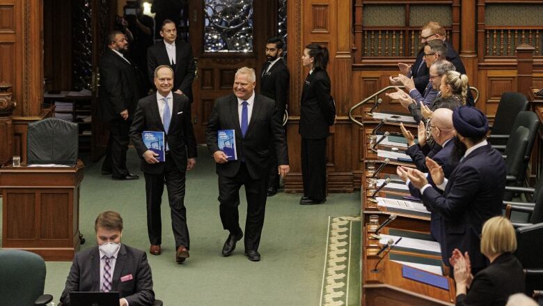 Premier Doug Ford and Finance Minister Peter Bethlenfalvy enter the chamber of the Ontario legislature with copies of the provincial budget on March 23, 2023.