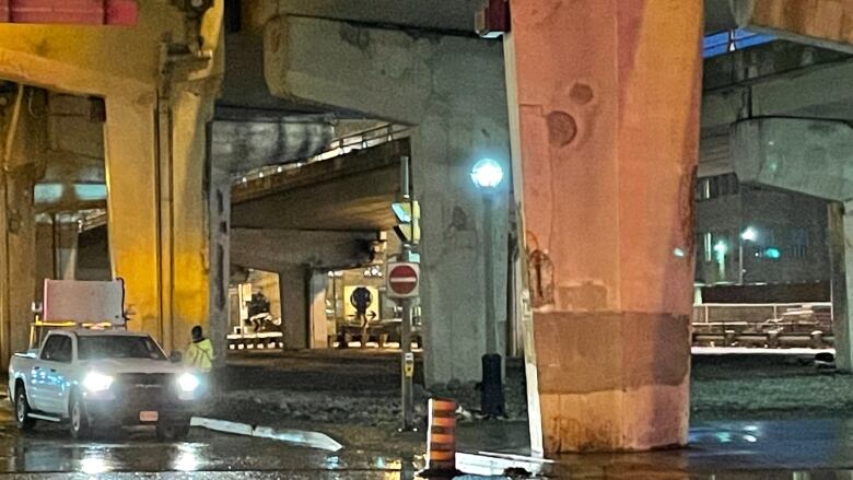 A photo of a vehicle stopped underneath the Gardiner Expressway. 