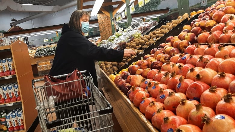 Someone shops in a supermarket's produce section.