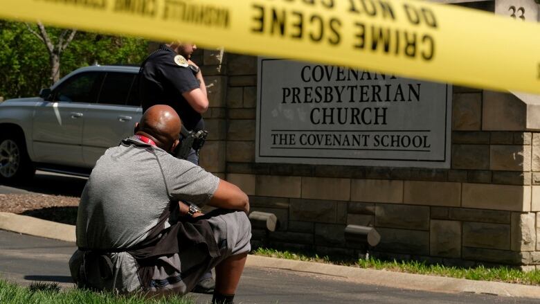 A man sits curbside in front of a sign for the Covenant Presbyterian Church.