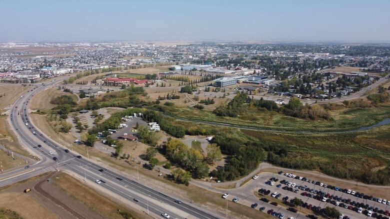 A twinned highway winds around an urban area surrounded by trees and water.