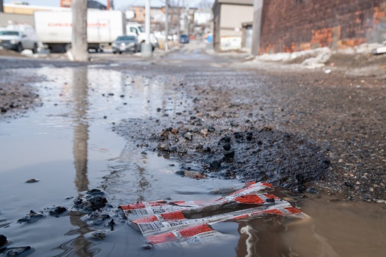 An empty syringe package in a puddle.