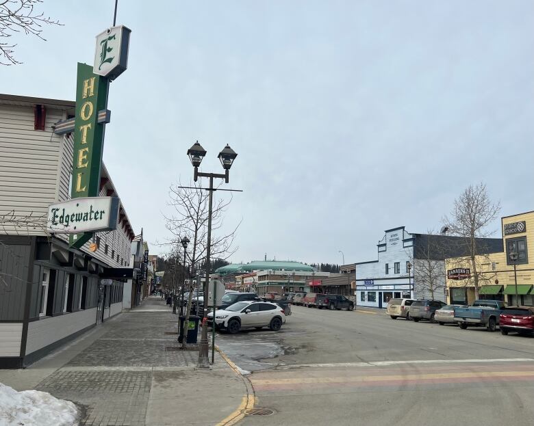 A view up a downtown street lined with parked cars. 