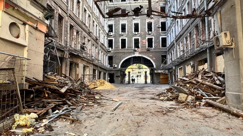 Rubble and pieces of broken lumber spill into a street lined with buildings in various states of disrepair in Kharkiv. 