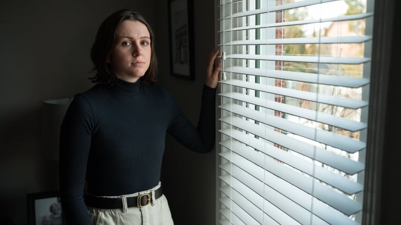 Olivia Roman, who has Crohn's disease, stands by a window in her family home. 