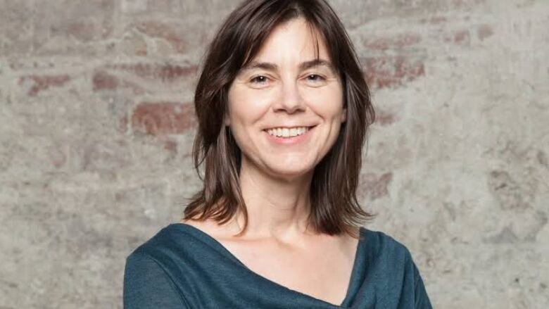 A woman in a green dress smiles widely at the camera.