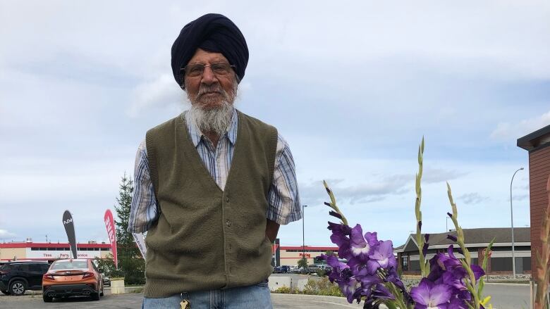 Man standing in front of flowers in a Canadian Tire parking lot.