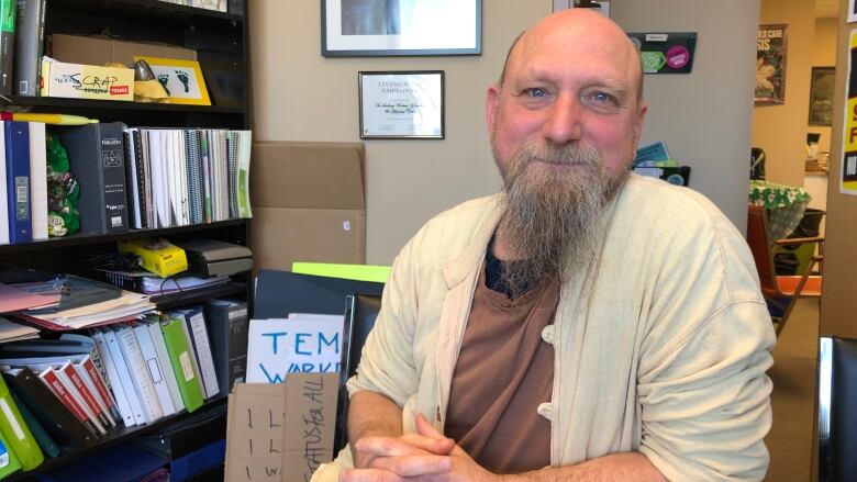 A middle aged man with a beard sitting in an office.