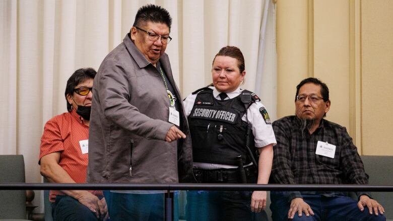 A man points down as a security guard stands beside him.