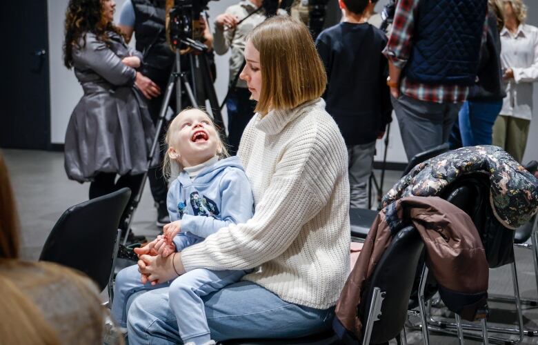 A woman is pictured holding her daughter who is laughing.