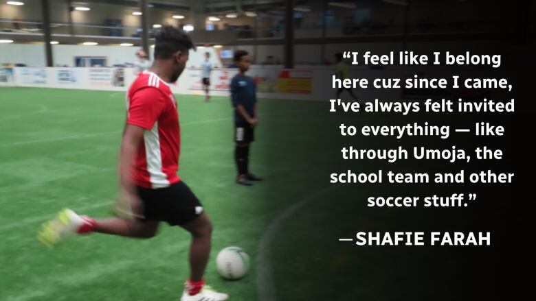 A boy kicks a soccer ball on indoor turf. 