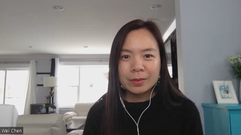 A woman wearing headphones looks at the camera in a living room. 