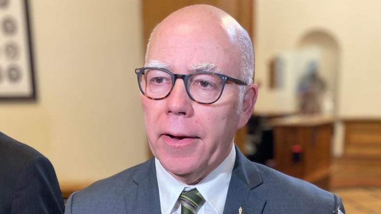 A balding man with glasses is speaking inside the legislature.