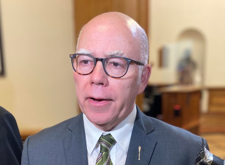 A balding man with glasses is speaking inside the legislature.