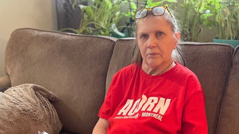 woman sits on couch holding papers