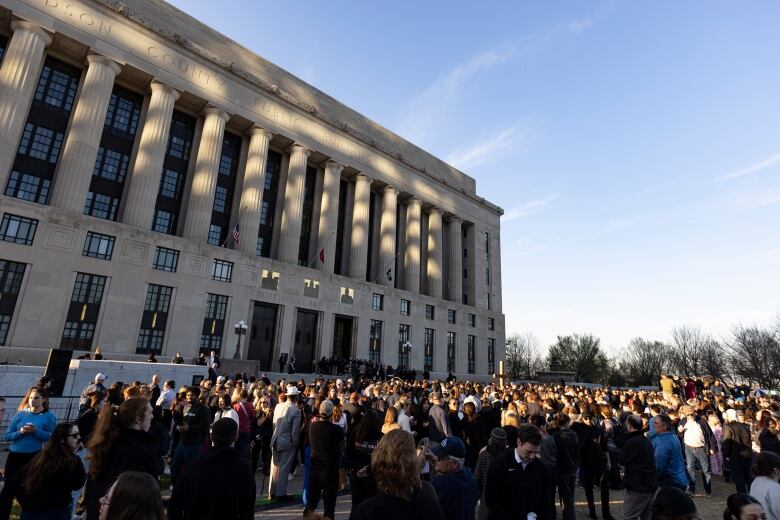 A large crowd gathers outside a government building.