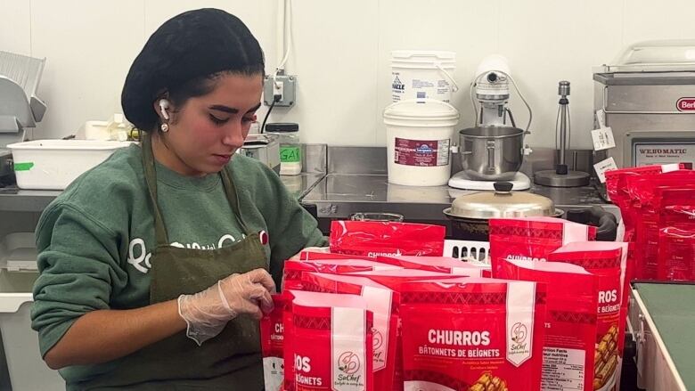 A woman fills bags of churros.