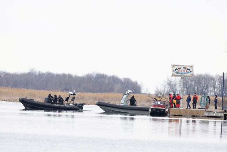 Three police boats at and around a dock in early spring.