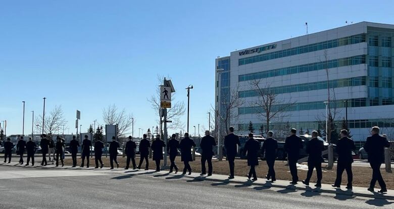 a row of men in suits walk in a line