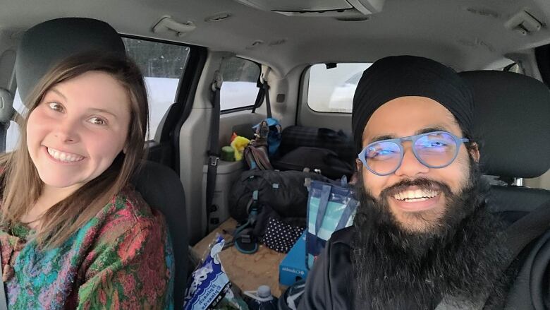 A woman and man sitting in the front seats of a vehicle smiling .