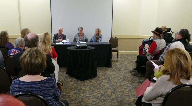 A room full of people listen during a panel discussion.