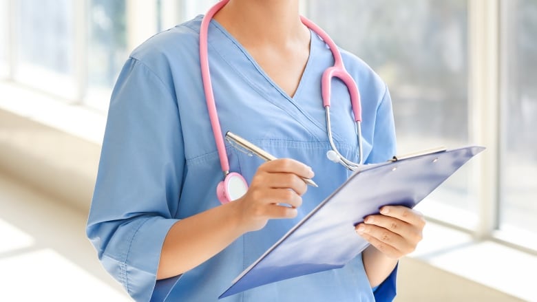 A young Black nurse in scrubs smiles for the camera.