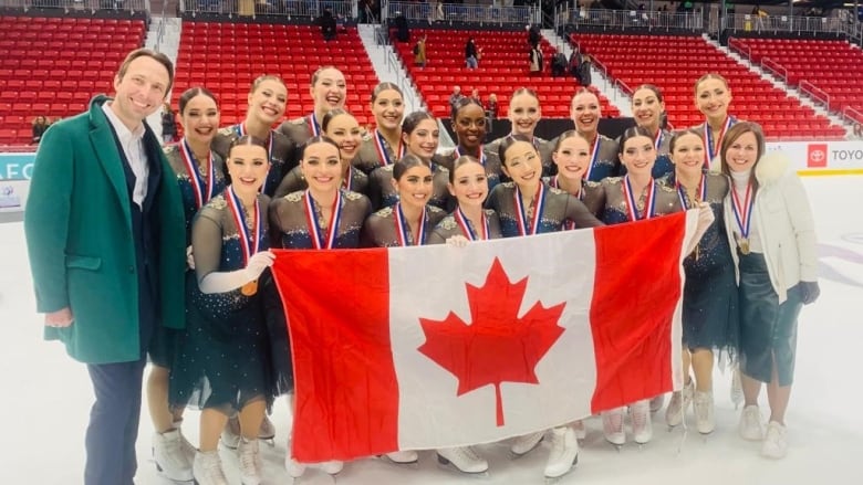 Les Suprmes, from St-Lonard, Que., celebrate with their gold medals and hold the Canadian flag at the ISU World Synchronized Skating Championships. 