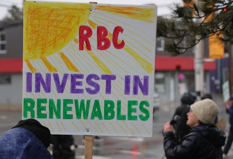 A protest sign says 'RBC invest in renewables'