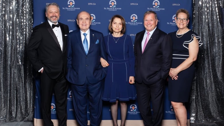 A group of five people in formal wear pose for the camera.